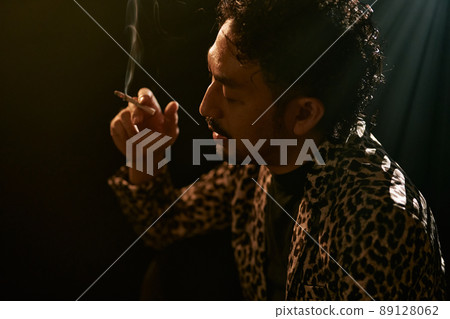 Bearded man in a leopard print jacket smoking a cigarette Bearded man in a leopard print jacket smoking a cigarette 89128062