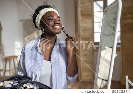 African woman near the mirror doing make up African woman near the mirror doing make up 89128274