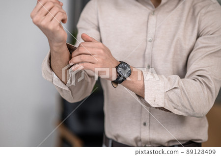 A man wearing a shirt and fastening cuffs A man wearing a shirt and fastening cuffs 89128409