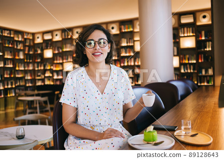 Content woman with coffee and dessert at cafe table 89128643