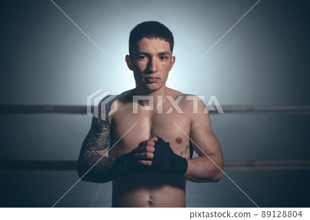 Boxer, man posing in bandage on boxing ring. Fitness and boxing concept. Boxer, man posing in bandage on boxing ring. Fitness and boxing concept. 89128804