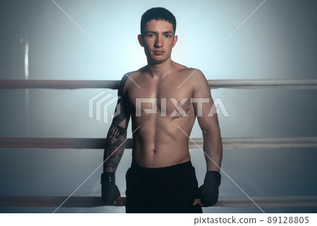 Boxer, man posing in bandage on boxing ring. Fitness and boxing concept. Boxer, man posing in bandage on boxing ring. Fitness and boxing concept. 89128805