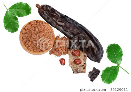 Carob pod and powder in wooden scoop isolated on white background with clipping path. Top view. Flat lay 89129011