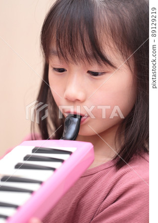 Girl playing keyboard harmonica 89129219