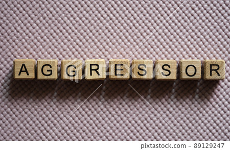 Aggressor written on wooden cubes on pink background closeup Aggressor written on wooden cubes on pink background closeup 89129247