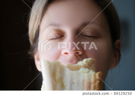Woman sniffing delicious fragrant piece of white bread Woman sniffing delicious fragrant piece of white bread 89129250