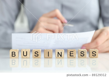 Woman manager studying documents near words business on wooden cubes closeup Woman manager studying documents near words business on wooden cubes closeup 89129312