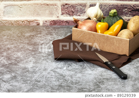 Cardboard box with fresh vegetables next to a knife. Vegetarian food. Healthy food Cardboard box with fresh vegetables next to a knife. Vegetarian food. Healthy food 89129339