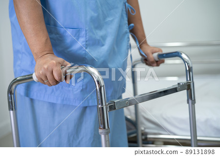 Asian lady woman patient walk with walker at nursing hospital ward, healthy strong medical concept Asian lady woman patient walk with walker at nursing hospital ward, healthy strong medical concept 89131898