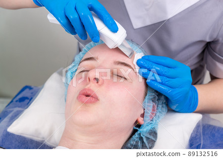 Young woman getting ultrasonic peel skin with skin scrubber. 89132516