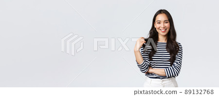 Lifestyle, people emotions and casual concept. Charming smiling korean girl in striped shirt, touching hair strand and grinning happily camera, talking to friend, white background Lifestyle, people emotions and casual concept. Charming smiling korean girl in striped shirt, touching hair strand and grinning happily camera, talking to friend, white background 89132768