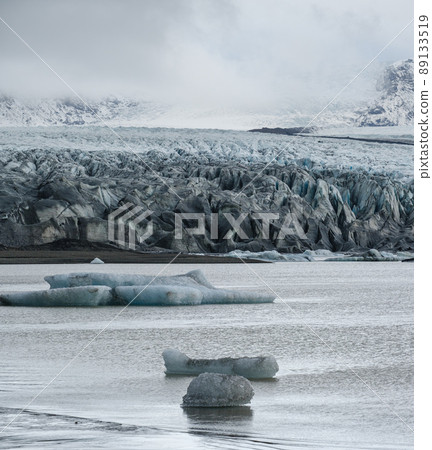 Skaftafellsjokull glacier, Iceland. Glacier tongue slides from the Vatnajokull icecap or Vatna Glacier near subglacial Esjufjoll volcano. Glacial lagoon with blocks of ice and surrounding mountains. Skaftafellsjokull glacier, Iceland. Glacier tongue slides from the Vatnajokull icecap or Vatna Glacier near subglacial Esjufjoll volcano. Glacial lagoon with blocks of ice and surrounding mountains. 89133519
