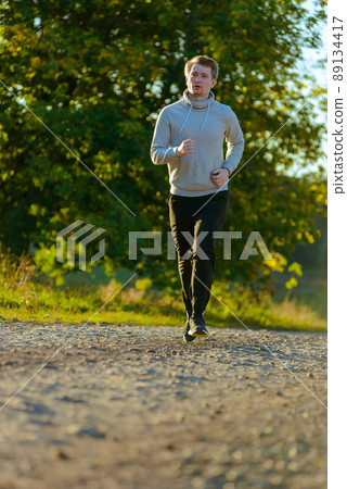 Man jogging in rural nature at beautiful summer day. Sport fitness model caucasian ethnicity training outdoor. Man jogging in rural nature at beautiful summer day. Sport fitness model caucasian ethnicity training outdoor. 89134417
