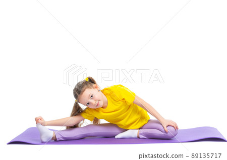Little cute girl is practicing stretching on a gymnastic mat. Isolated on white background. 89135717