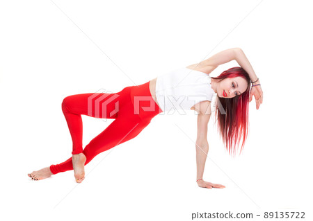 A beautiful, athletic, slim, smiling and cheerful woman in a white top and red sweatpants performs stretching and Pilates elements. Lifestyle concept with sports and gym, healthy lifestyle. Isolated A beautiful, athletic, slim, smiling and cheerful woman in a white top and red sweatpants performs stretching and Pilates elements. Lifestyle concept with sports and gym, healthy lifestyle. Isolated 89135722