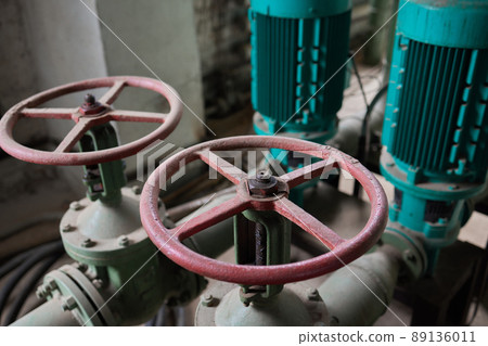 Close-up at pipeline valve which is using to control production process in the oil refinery plant. Selective focus at the valve handle wheel, Heavy industrial object photo. 89136011