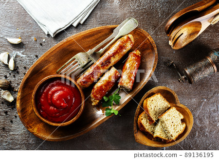 Fried sausages with sauces and herbs on a wooden serving Board. Great beer snack on a dark background. Top view with copy space 89136195