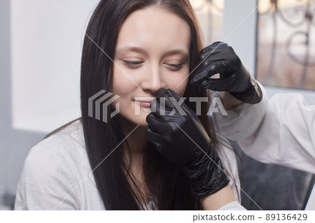 piercings on an ear. Conch and helix piercings close up. Professional holding the jewel. 89136429