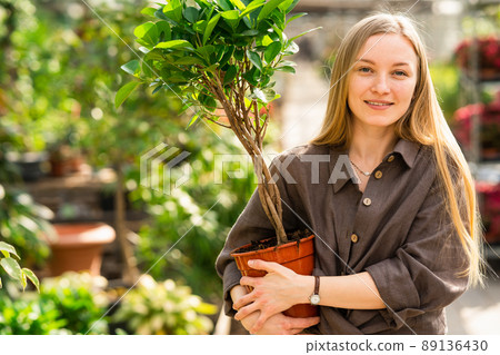 Portrait of a pretty girl florist with a flowerpot in her hands at the garden center Portrait of a pretty girl florist with a flowerpot in her hands at the garden center 89136430