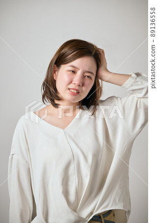 A young woman with a headache and holding her head with her hands A young woman with a headache and holding her head with her hands 89136558