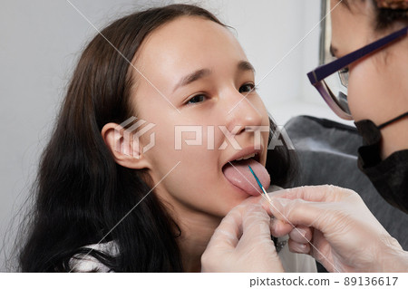 Tongue piercing operation Professional holding the jewel. Tongue piercing operation Professional holding the jewel. 89136617