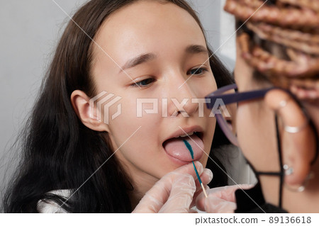 Tongue piercing operation Professional holding the jewel. Tongue piercing operation Professional holding the jewel. 89136618