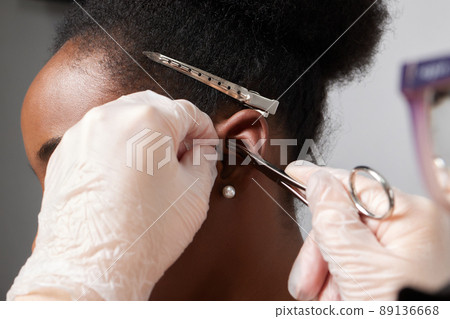 Close up of woman's ear with pierced on her ear for treatment of the pain some place on her body by Chinese doctor. Close up of woman's ear with pierced on her ear for treatment of the pain some place on her body by Chinese doctor. 89136668