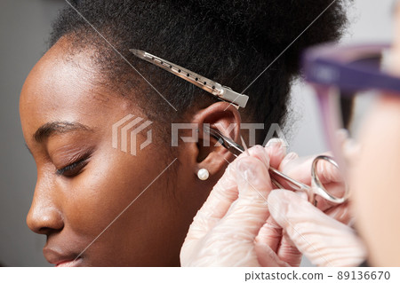 Close up of woman's ear with pierced on her ear for treatment of the pain some place on her body by Chinese doctor. Close up of woman's ear with pierced on her ear for treatment of the pain some place on her body by Chinese doctor. 89136670
