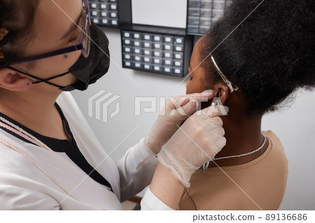 Close up of woman's ear with pierced on her ear for treatment of the pain some place on her body by Chinese doctor. Close up of woman's ear with pierced on her ear for treatment of the pain some place on her body by Chinese doctor. 89136686