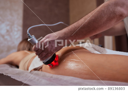 Hardware figure correction. Machine cosmetology. Beautiful woman having cavitation, procedure removing cellulite on her buttocks. 89136803