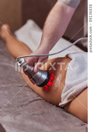 Hardware figure correction. Machine cosmetology. Beautiful woman having cavitation, procedure removing cellulite on her buttocks. 89136838