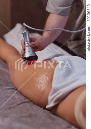 Hardware figure correction. Machine cosmetology. Beautiful woman having cavitation, procedure removing cellulite on her buttocks. Hardware figure correction. Machine cosmetology. Beautiful woman having cavitation, procedure removing cellulite on her buttocks. 89136840