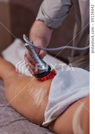 Hardware figure correction. Machine cosmetology. Beautiful woman having cavitation, procedure removing cellulite on her buttocks. 89136842