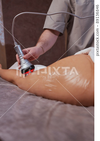 Hardware figure correction. Machine cosmetology. Beautiful woman having cavitation, procedure removing cellulite on her buttocks. 89136846