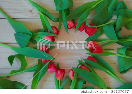 Pink tulips with green leaves lie in a circle with a free place in the center on a wooden background. High quality photo Pink tulips with green leaves lie in a circle with a free place in the center on a wooden background. High quality photo 89137077