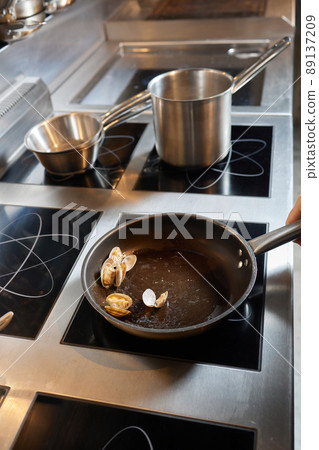 Chef frying mussels on commercial kitchen in restaurant, close-up on hands. 89137209
