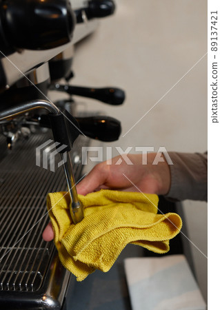 A perfectly lit cleaning cloth sat upon an espresso machine. 89137421