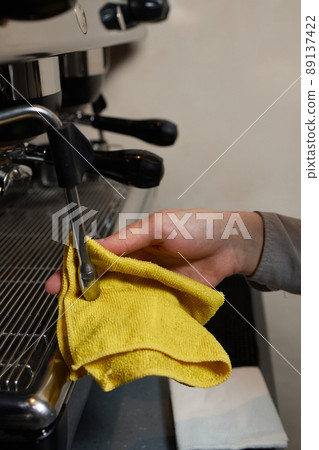 A perfectly lit cleaning cloth sat upon an espresso machine. 89137422