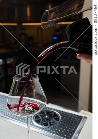 Sommelier man pours red wine into decanter for aeration of taste and aroma. Sommelier man pours red wine into decanter for aeration of taste and aroma. 89137464