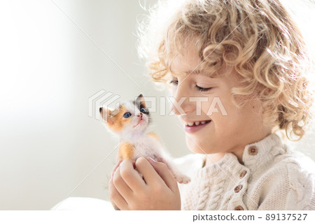 Child playing with kitten. Cat and kid at home. 89137527