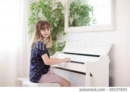 Child playing piano. Kids play music. 89137693