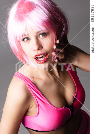 Face of a young woman with bright makeup on a pink background with gathered hair in a smooth ponytail. 89137953
