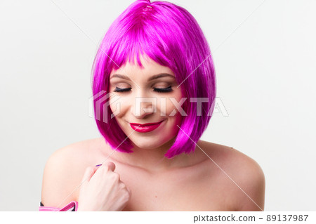 Face of a young woman with bright makeup on a pink background with gathered hair in a smooth ponytail. Face of a young woman with bright makeup on a pink background with gathered hair in a smooth ponytail. 89137987
