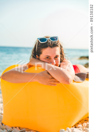 woman sunbathing at sea beach laying on yellow air sofa woman sunbathing at sea beach laying on yellow air sofa 89138182