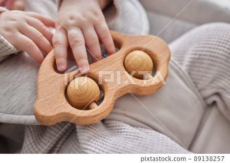Close-up of a baby s hand, playing with a wooden toy. Unfocused background. 89138257