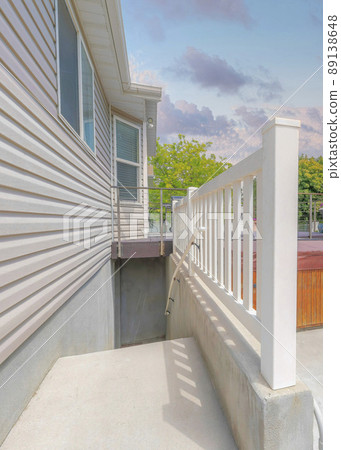 Vertical Puffy clouds at sunset Narrow basement entrance with railings beside the wood viinyl si 89138648