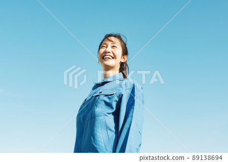 Blue sky portrait of a woman in work clothes Blue sky portrait of a woman in work clothes 89138694