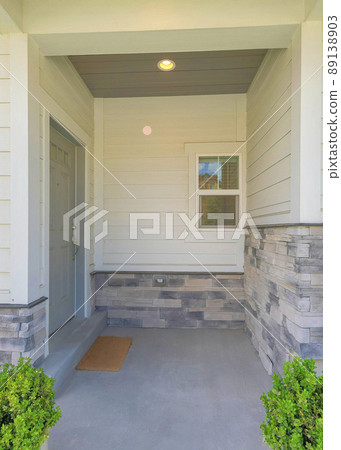 Vertical Entrance of a house with gray door on the side and two potted plants near the column posts Vertical Entrance of a house with gray door on the side and two potted plants near the column posts 89138903