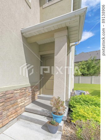 Vertical Whispy white clouds Entrance of a house at the side of the wall with stone veneer Vertical Whispy white clouds Entrance of a house at the side of the wall with stone veneer 89138906