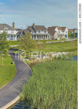Vertical Whispy white clouds Oquirrh Lake at Daybreak in Utah with paved sidewalk on the side 89139080